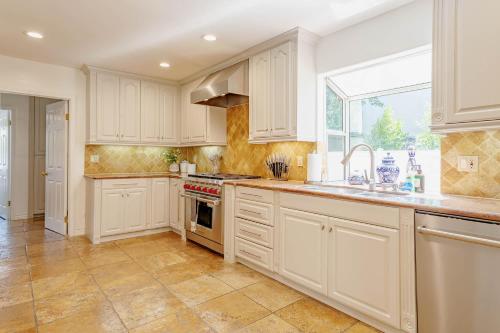 a kitchen with white cabinets and a large window at Cozy Home with Pool and Jacuzzi Minutes from Universal Studios in Los Angeles