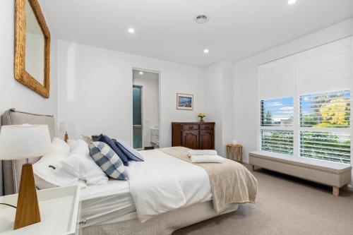 a white bedroom with a bed and a window at Grandview on Bayview in Inverloch