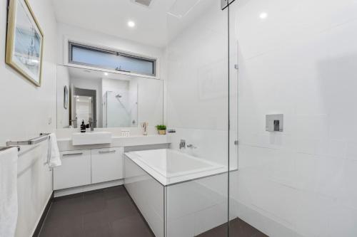a white bathroom with a sink and a shower at Grandview on Bayview in Inverloch