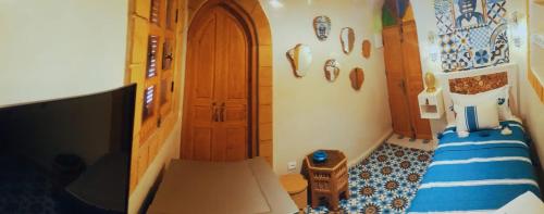 a small bedroom with a bed and a tv in it at Dar Milal in Essaouira