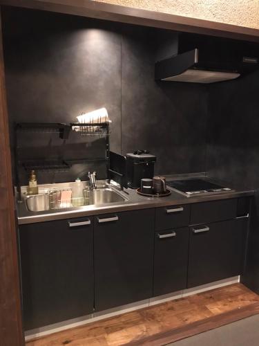 a kitchen with a sink and a stove at 瀬戸内サウナホテル月 in Takamatsu
