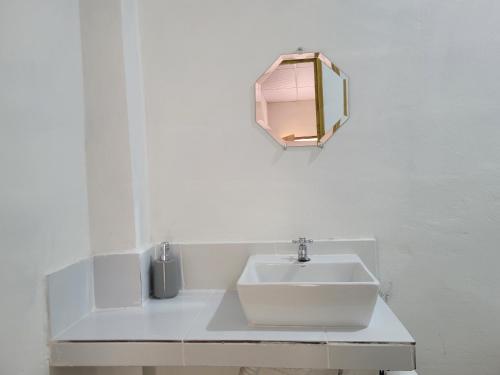 a white bathroom with a sink and a mirror at Mi pueblo Hostal Nahuizalco in Nahuizalco