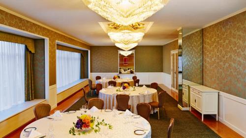 a dining room with tables and chairs and a chandelier at RIHGA Royal Hotel Osaka, Vignette Collection by IHG in Osaka