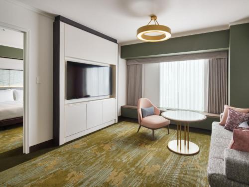 a hotel room with a couch and a table and a tv at RIHGA Royal Hotel Osaka, Vignette Collection by IHG in Osaka