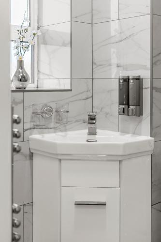 a white bathroom with a sink and a mirror at Jasmine Suite by Yielding Bricks in London