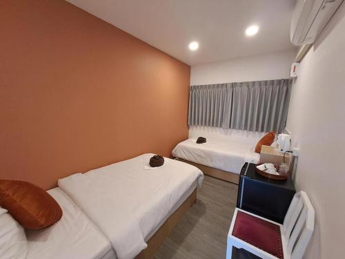a small room with two beds and a table at Nomads Homestay Sriracha in Chon Buri