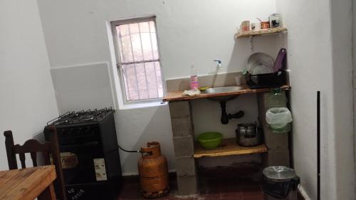 een keuken met een fornuis, een wastafel en een raam bij Sol de la cumbre in La Cumbre