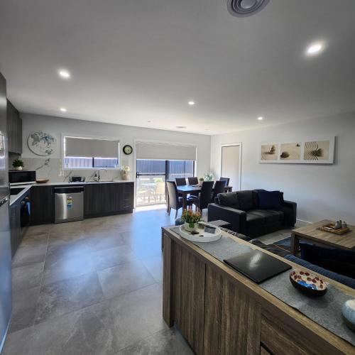 a large living room with a couch and a kitchen at Lbarza Elegant Family 3BR Townhouse close to shopping centre Kialla in Kialla