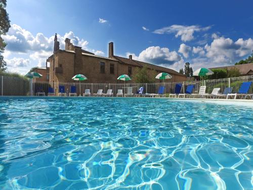 une piscine avec des chaises et un bâtiment en arrière-plan dans l'établissement Chalet in Nedde near Historic Castle, à Légaud