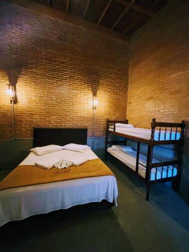 a bedroom with two bunk beds in a brick wall at La Villa Chalés in Serra Negra