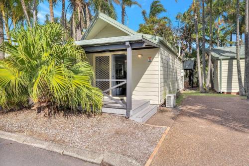 a small house with a porch with palm trees at Ingenia Holidays One Mile Beach in One Mile