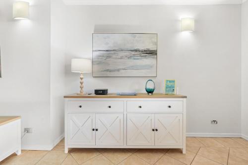 a white dresser with a lamp on top of it at Harbour Haven Penthouse with Marina view, Balcony and BBQ in Larrakeyah