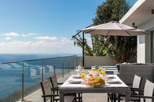a table with a plate of food on a balcony at Villa Harmonia by Homie in Ponta do Sol