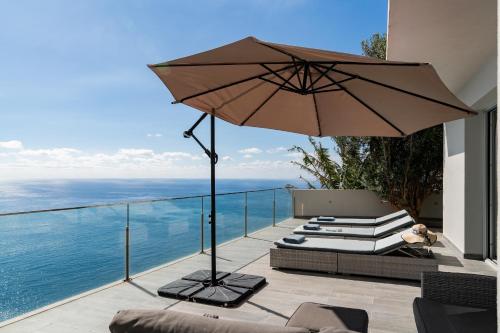a patio with an umbrella and a chair and books at Villa Harmonia by Homie in Ponta do Sol