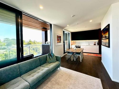 Una sala de estar con un sofá verde y una mesa. en 1BR with Balcony Close to Ferry by Zodiak Stays, en Auckland