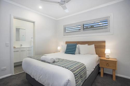 a bedroom with a large bed with a night stand and a window at Ingenia Holidays One Mile Beach in One Mile