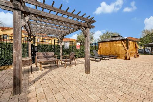 a wooden pergola with two chairs and a bench at Home Near Disney Private Pool & Playground in Howey in the Hills