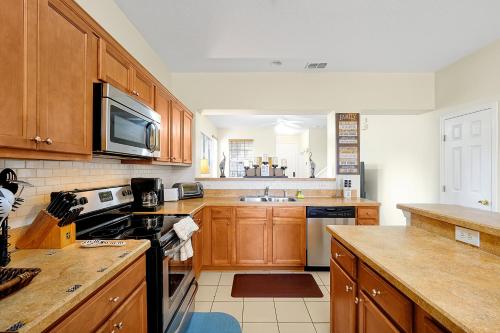 a kitchen with wooden cabinets and a stove top oven at Home Near Disney Private Pool & Playground in Howey in the Hills