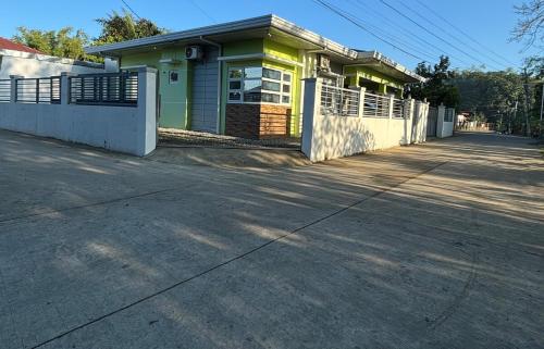 a yellow and green house with a white fence at Heritage Haven Guesthouse in Vigan