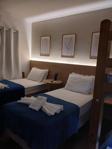 two beds in a hotel room with towels on them at Pousada Bem te vi in Bragança Paulista