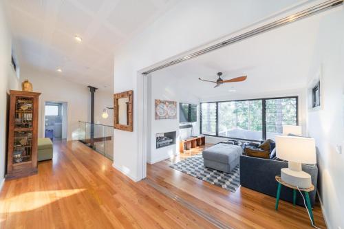 a living room with white walls and wood floors at Mossy Green Door MTB stay minutes to Mogo Trails in Mossy Point