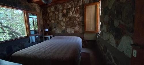 a bedroom with a bed and a stone wall at FUJI - Casas para relajar in Villa de Las Rosas