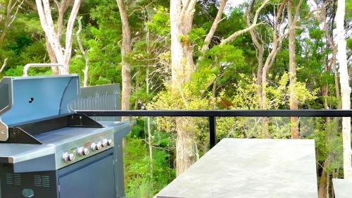 una parrilla azul en un balcón con árboles en el fondo en Paihia Lighthouse, en Paihia