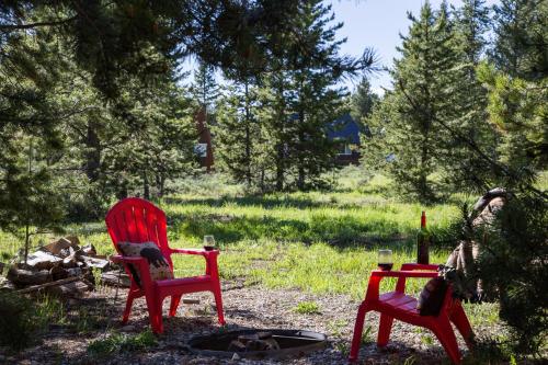 two red chairs sitting around a fire in a yard at Rimfire Refuge in Island Park