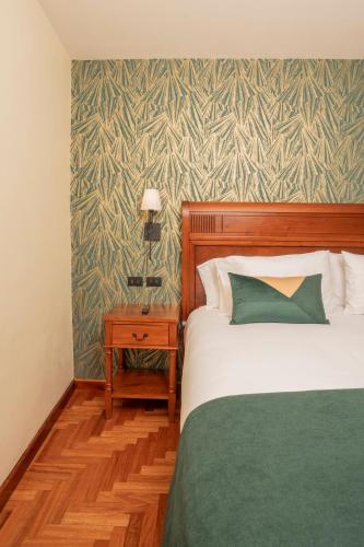 a bedroom with a bed and a table with a lamp at Centenario Hotel Boutique in Quetzaltenango