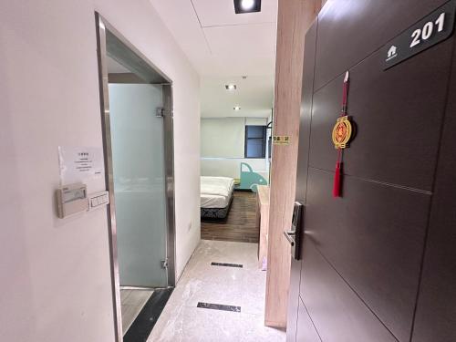 a hallway with a door to a room with a bed at π 園周綠溫泉會館-泉鄉雅舍 in Jiaoxi