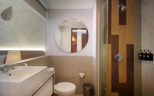 a bathroom with a sink and a toilet and a mirror at Nadi Hotel Legian in Legian