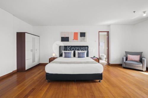 ein Schlafzimmer mit einem großen Bett und einem Stuhl in der Unterkunft Tovia by Kozystay - Senayan in Jakarta