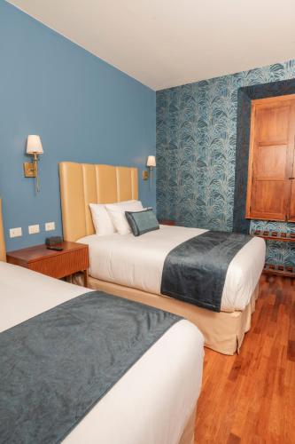 a hotel room with two beds and blue walls at Centenario Hotel Boutique in Quetzaltenango