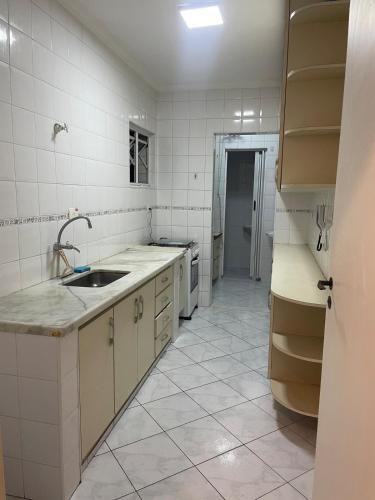 a white kitchen with a sink and a tiled floor at Apartamento Guarujá - Praia Enseada in Guarujá