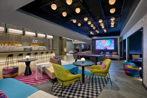 a lobby with tables and chairs and a tv at Aloft Bangkok - Sukhumvit 11 in Bangkok