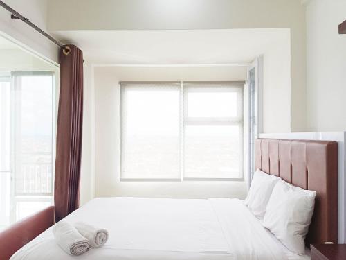 a bedroom with a bed and a window at Comfort 1BR at Vida View Makassar Apartment By Travelio in Pampang