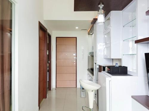 a white kitchen with a sink and a door at Comfort 1BR at Vida View Makassar Apartment By Travelio in Pampang