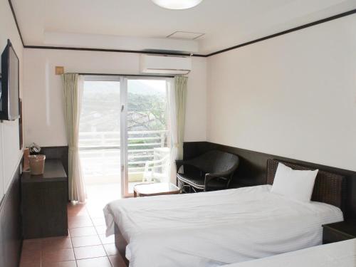 a hotel room with a bed and a balcony at Pine Shima Resort Coral Fish in Ibaruma