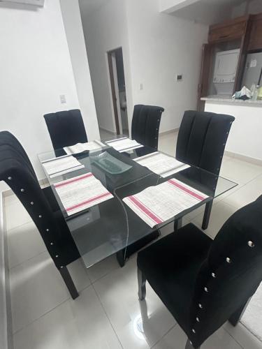 a dining room table with black chairs and a glass table at Brand New Beachfront Sunset Apartments in San Felipe de Puerto Plata