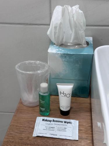 a counter with a box and a bottle of makeup remover wipes and a cup at Brand New Beachfront Sunset Apartments in San Felipe de Puerto Plata