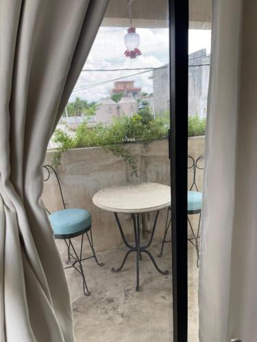 a table and chairs on a balcony with a window at Casa colibrí in Río Lagartos