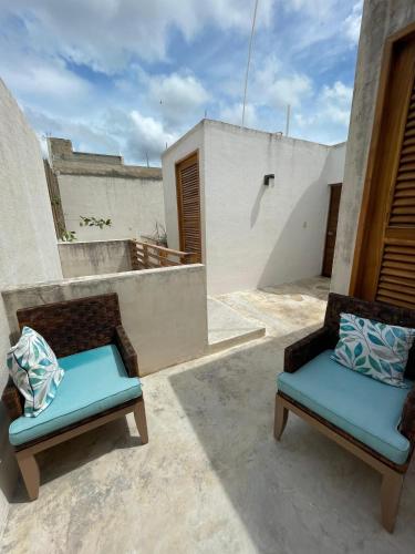 a patio with two chairs and a table at Casa colibrí in Río Lagartos