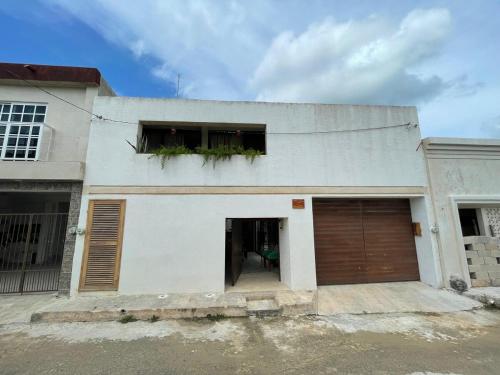 a white house with two windows and a garage at Casa colibrí in Río Lagartos