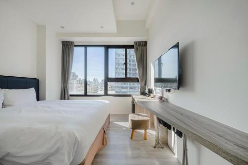 a bedroom with a bed and a desk with a tv at CHECK inn Express Taichung Fuxing in Taichung