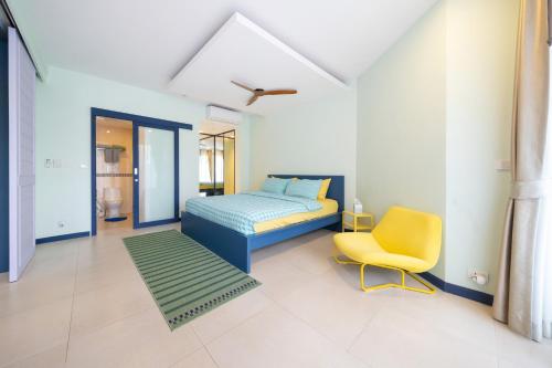une chambre avec un lit et une chaise jaune dans l'établissement Allamanda Laguna Phuket, à Laguna Phuket