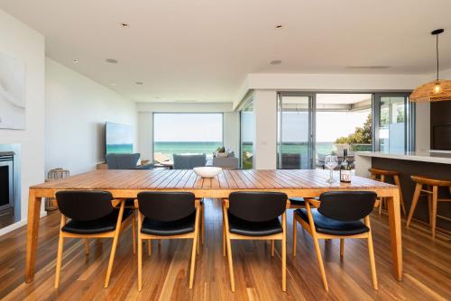 a dining room with a large wooden table and chairs at Gracie on the Beach Luxe with Water Views in Edithvale
