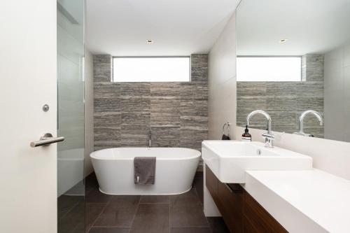a bathroom with a white tub and a sink at Gracie on the Beach Luxe with Water Views in Edithvale
