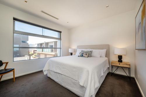 a white bedroom with a bed and a large window at Gracie on the Beach Luxe with Water Views in Edithvale
