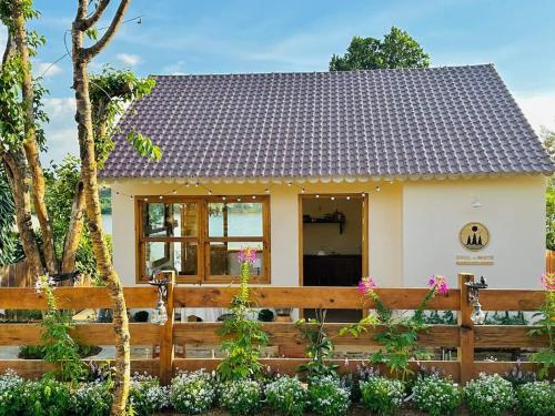 a small white house with a wooden fence at Nhà Bên Hồ- The Peace's House in Bao Loc