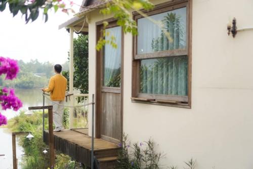 a man standing on the porch of a house at Nhà Bên Hồ- The Peace's House in Bao Loc